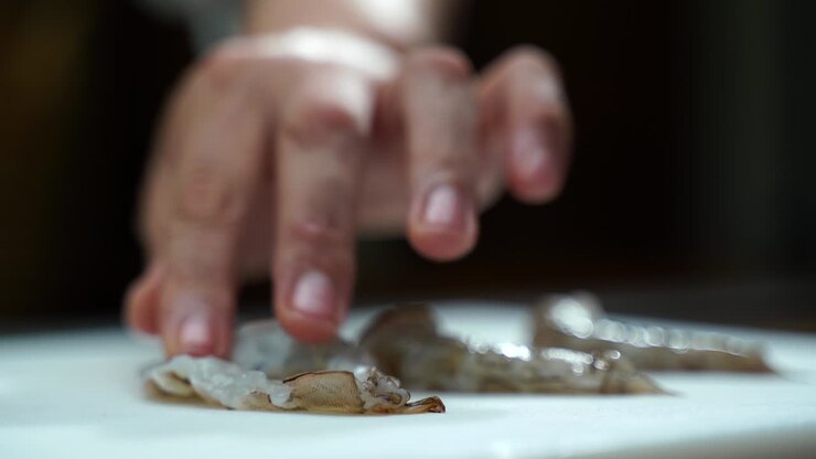 Mexican Latin cooker Chef slicing fresh shrimps in to half butterfly cut close up