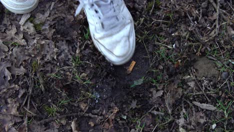 girl hesitant about stamping out thrown cigarette on the ground