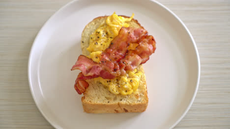 bread-toast-with-scramble-egg-and-bacon-on-white-plate