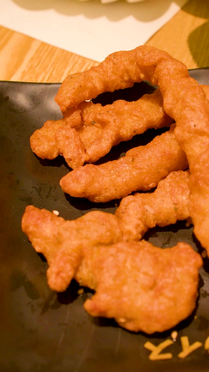 Primo piano di striscioline di pollo fritto croccanti mentre vengono prese con le bacchette.