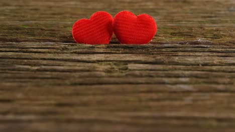 dos corazones rojos metidos en la tabla de madera 4k