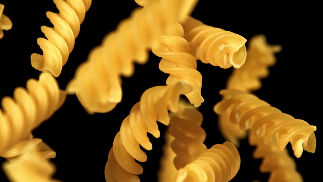 Pasta fusilli secca che cade e galleggia al rallentatore