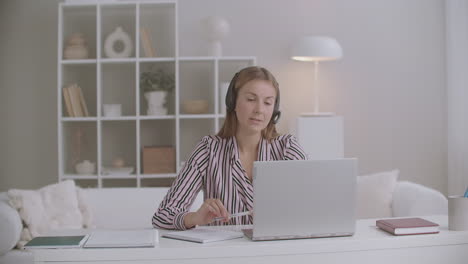 female student is giving exam of foreign language online talking by video chat on laptop distant mode