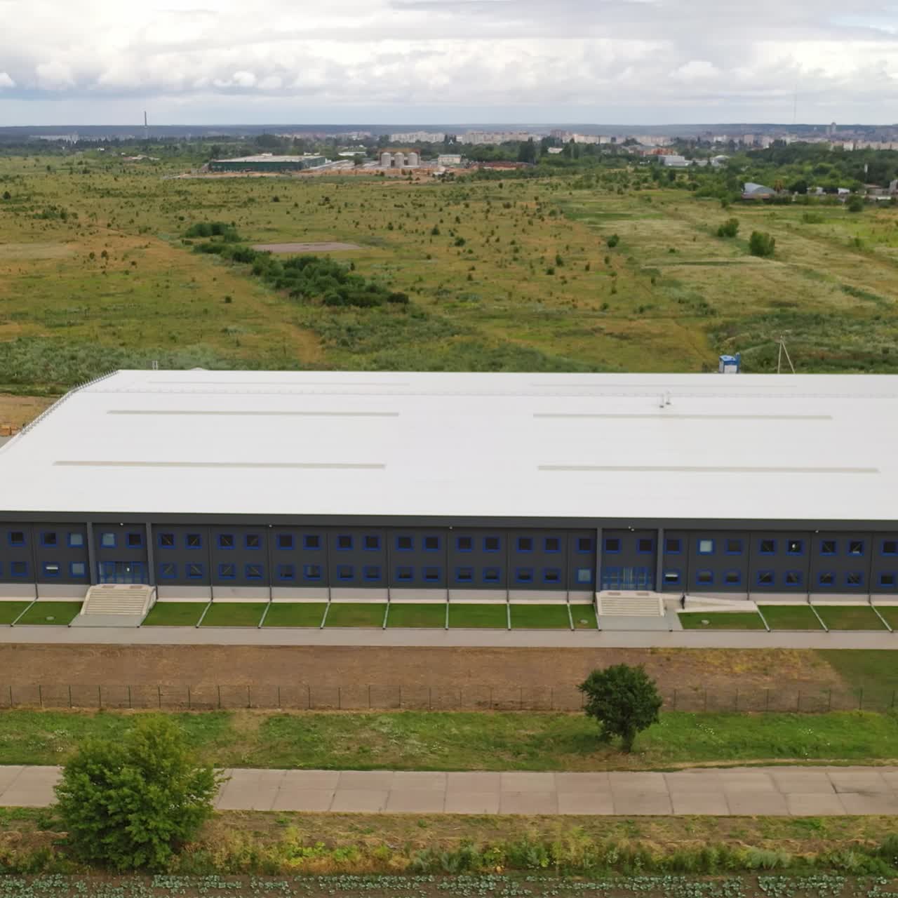 Aerial view of a large industrial building surrounded by green fields