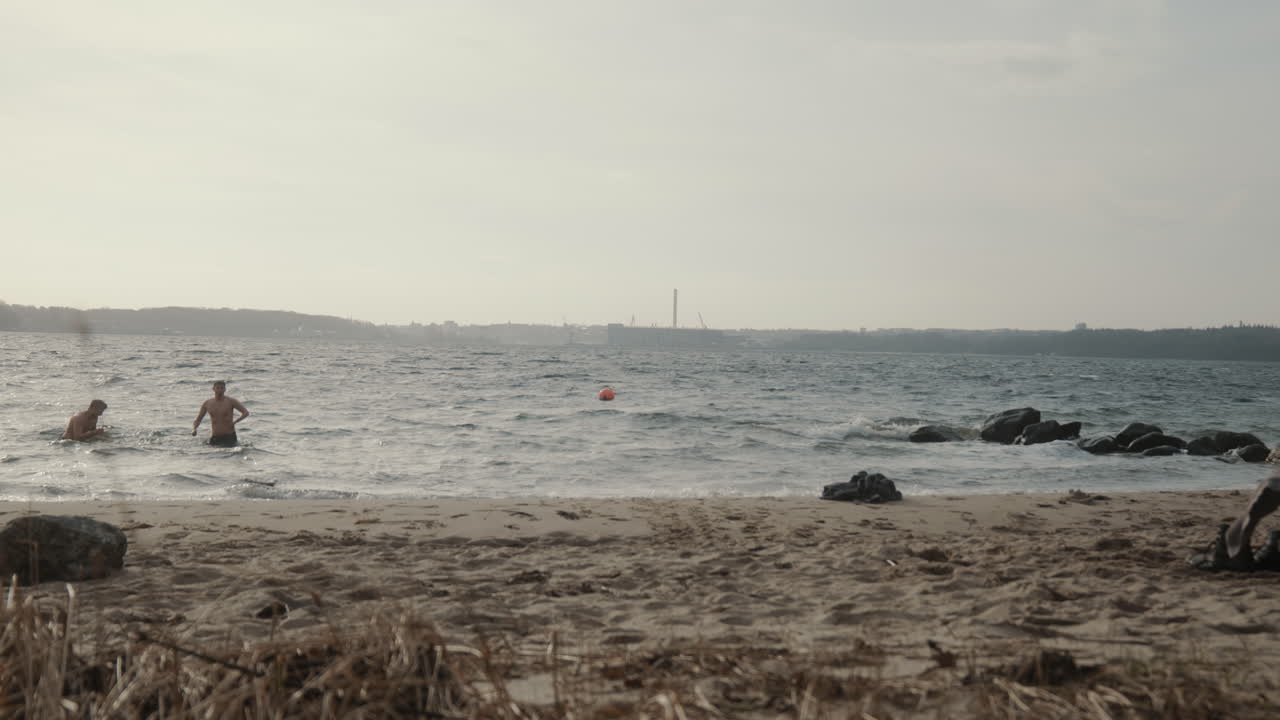 Two young males bathing in the cold water in January near the beach