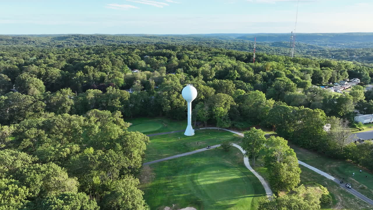 Water Tower At East Mountain Golf Course Surrounded By Green Forest In Waterbury, Connecticut, USA. - aerial shot