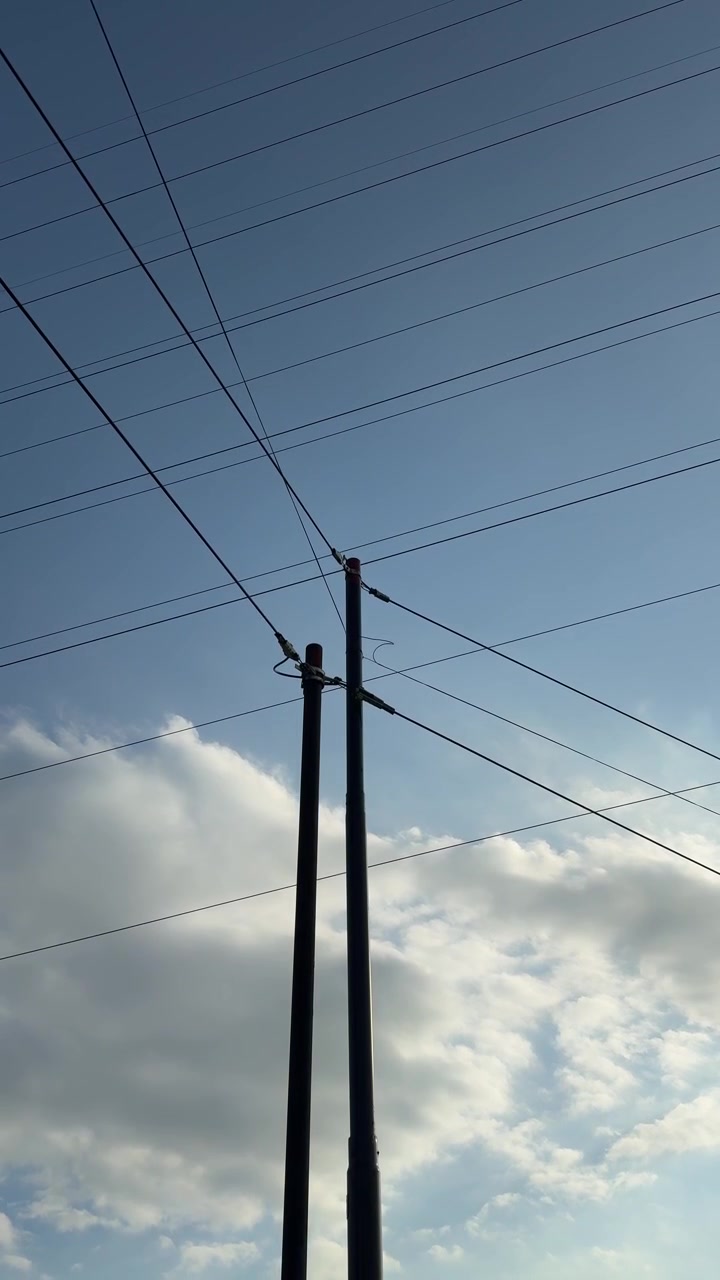 Utility Poles and Power Lines Against a Cloudy Blue Sky