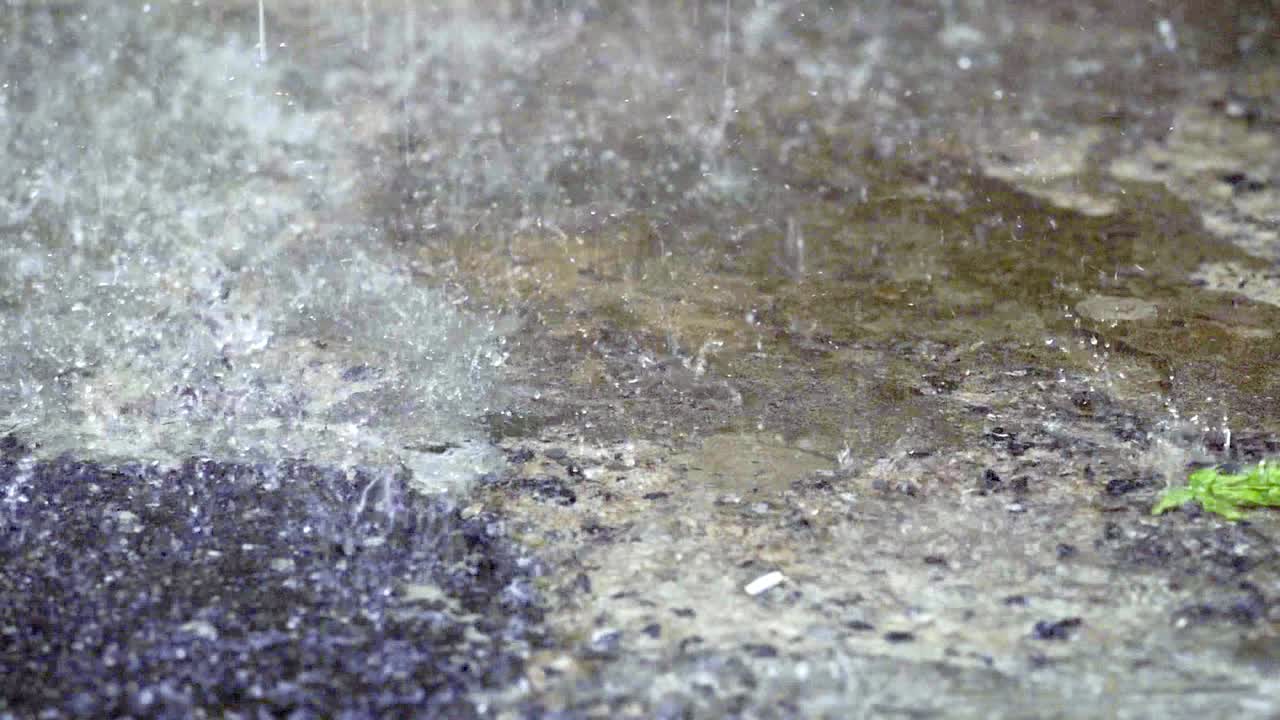 Slow motion close up of Raining drop falling on the street concrete, vintage film look