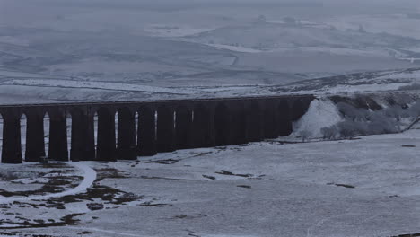 Pullback-Establishing-Aerial-Drone-Shot-of-Snowy-Ribblehead-Viaduct-in-Yorkshire-Dales-UK