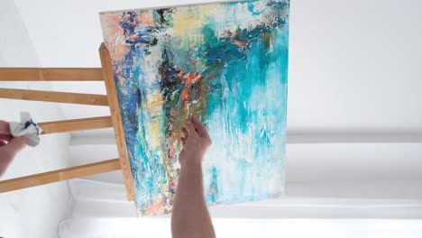 artist painting abstract art on an easel in a studio