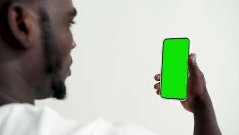 young person touch screen smartphone with green chroma key close-up. guy tapping gesture on cell phone mock-up. concept watch and show internet social media, calls, read news, app, iot, e-shopping 4k