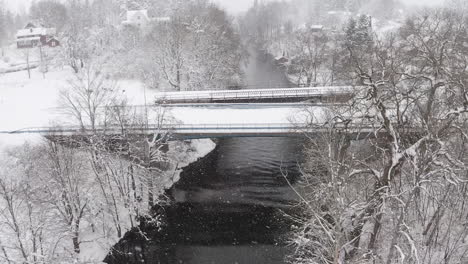 aerial view of a snow covered bridge over a river on a winter day in sweden