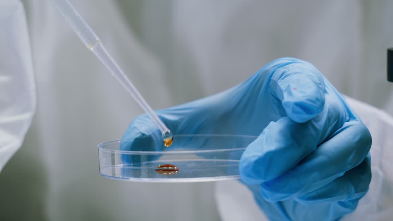 Close-up of Scientist's Hand Dropping Liquid into Petri Dish