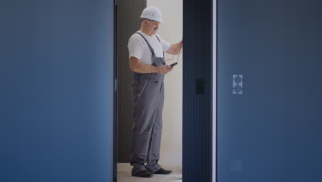 el electricista comprueba el funcionamiento de la unidad de control de pared de las lámparas con el sistema de la casa moderna después de la instalación y reparación