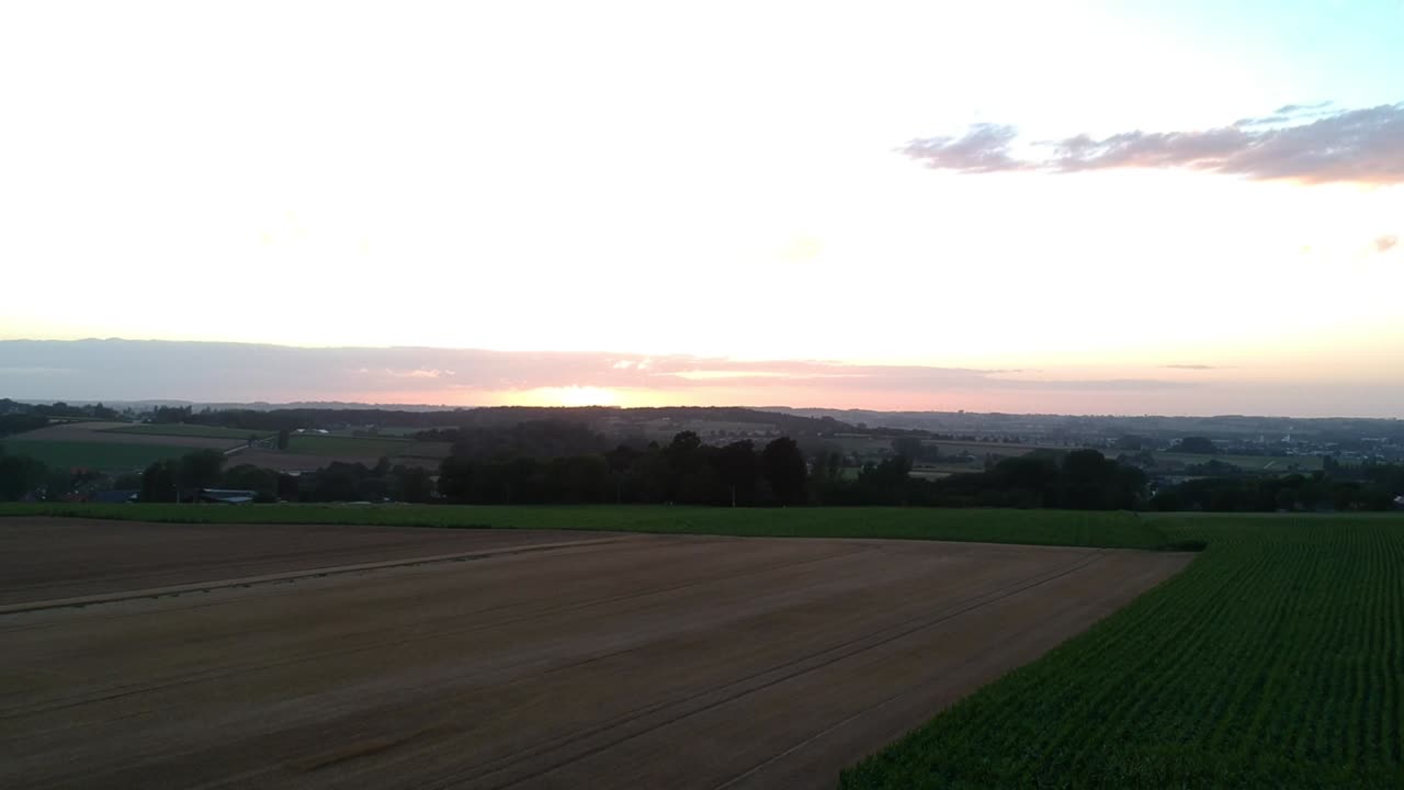 Rise above crop fields and valley at sunset, drone shot