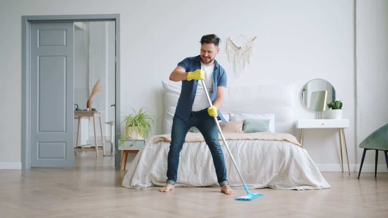 Man Having Fun While Mopping the Bedroom Floor