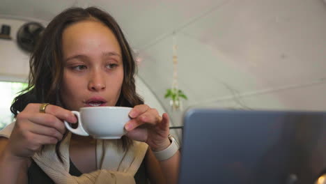 Slow-motion-close-up-shot-of-a-pretty-businesswoman-drinking-her-coffee-whilst-working