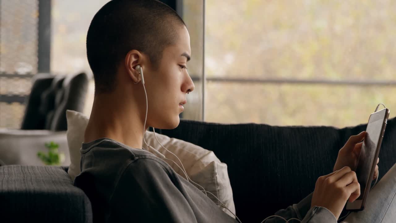 Man listening music while using digital tablet at home 4k