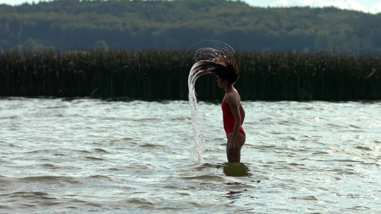 la mujer salpicando el agua con el pelo mojado sumergido en el agua del lago