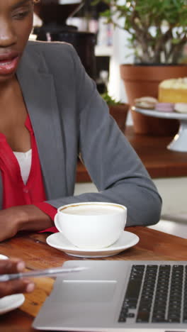 hombre y mujer usando una computadora portátil mientras toman una taza de café
