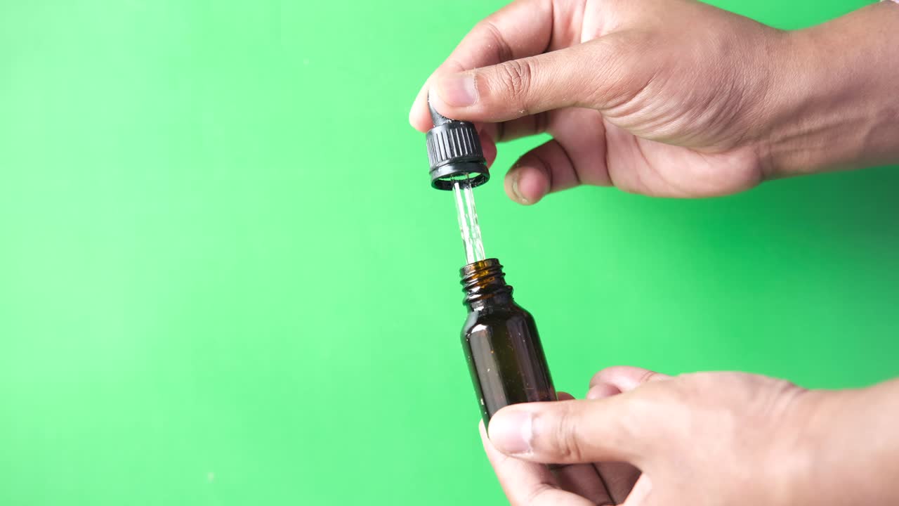 persona que sostiene una botella de gotero