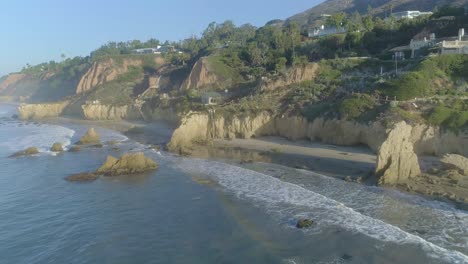 Aerial-shots-of-El-Matador-beach-over-breaking-waves-and-rocks-on-a-hazy-summer-morning-in-Malibu,-California