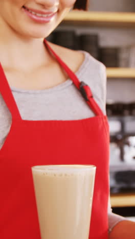 smiling waitress carrying two cold coffees in cafe