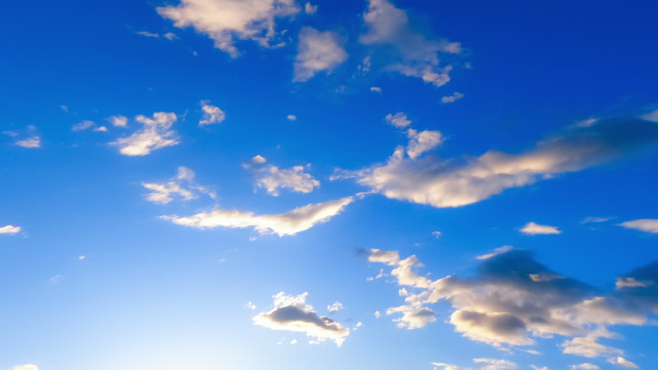 Pleasant beautiful azure sky in summer. Some light fluffy clouds float by the atmosphere. Low angle view. Timelapse.