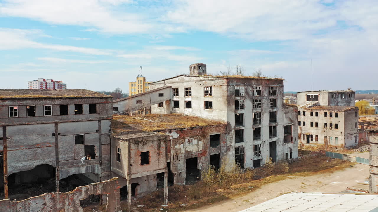 Vista aerea di edifici abbandonati, distrutti dopo azioni militari. Architettura industriale distrutta con finestre rotte e grandi buchi. La telecamera avanza.