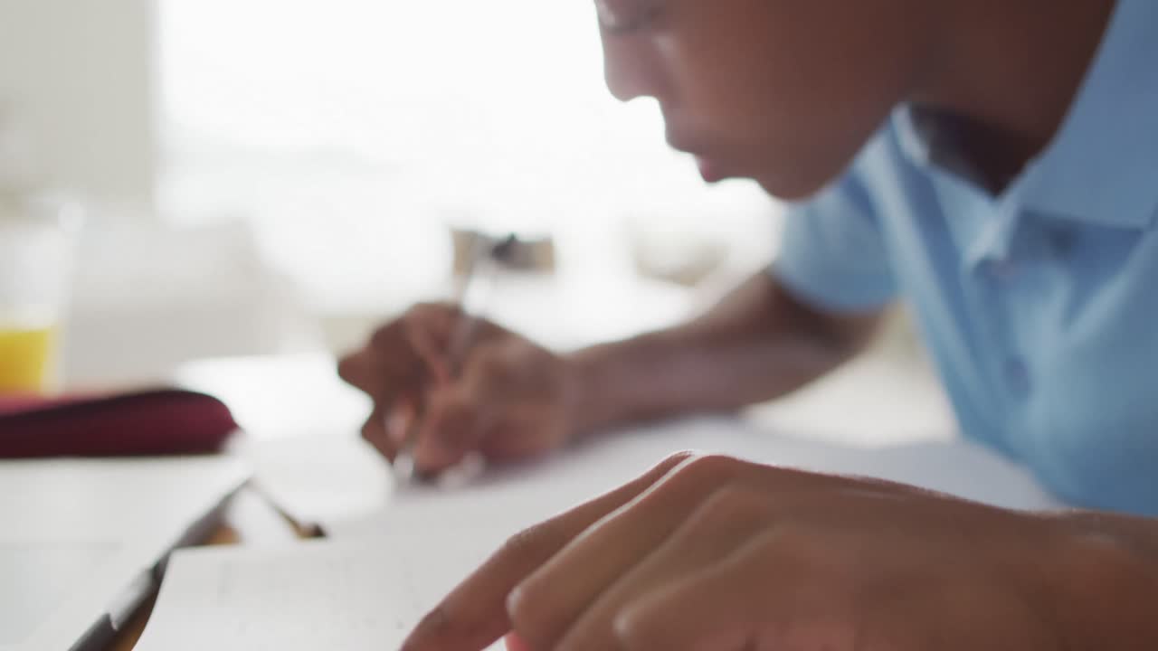 Video of focused african american boy having online lessons at home