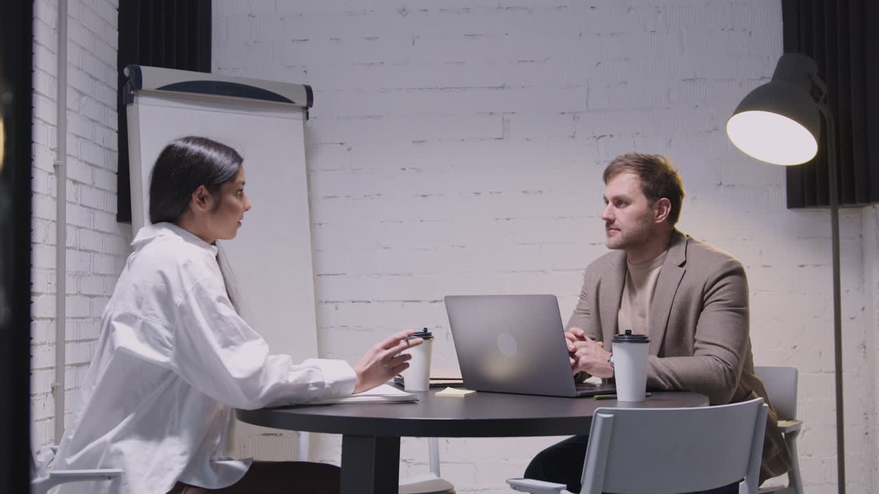 мужчина и женщина проводят деловую встречу и разговаривают вместе, сидя за столом в зале заседаний