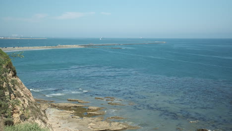 Pacific-Waves-Flowing-to-Shore-of-the-Bluff,-Coastal-California-South-Bay-Views-Featuring-Rocky-Cliff,-Winding-Jetty-and-Kelp-Forest