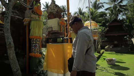 Balinese-guy-is-splash-holy-water-ritual-praying-temple,-slowmo