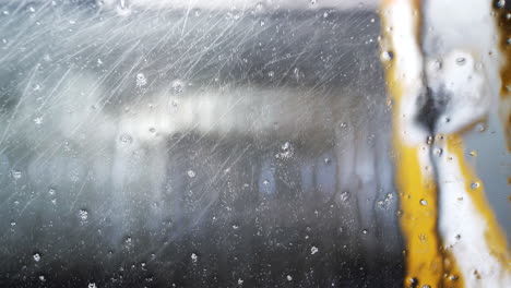 Gotas-De-Agua-Y-Espuma-En-La-Ventana-Del-Vehículo-Dentro-Del-Lavado-Automático-De-Autos