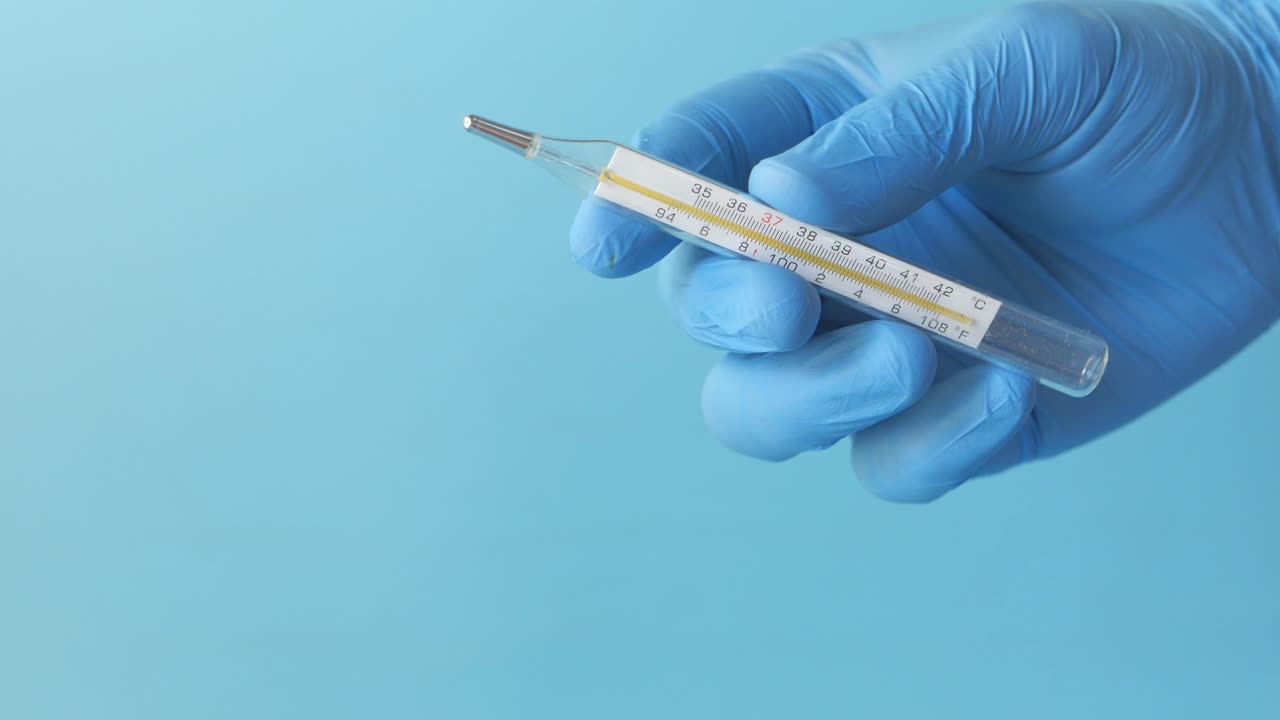 termómetro médico en una mano con guante