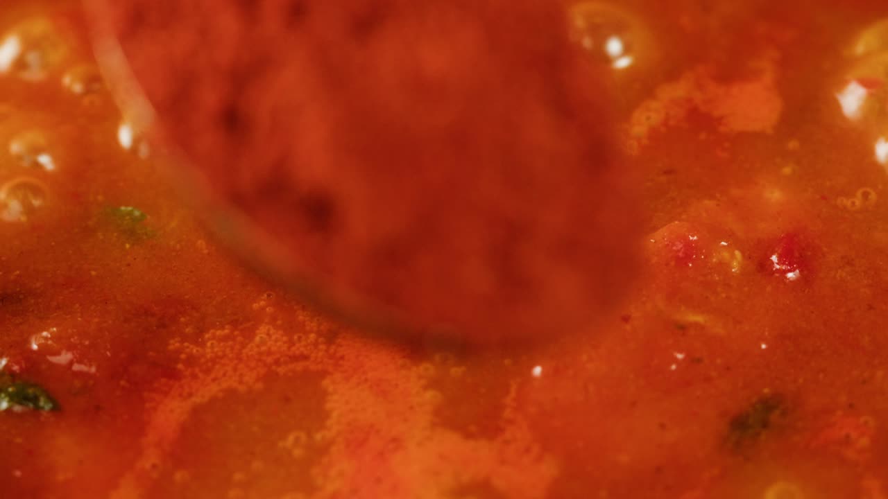 Boiling tomato sauce on a frying pan close-up. Cooking tomato sauce or soup. Traditional Italian Mexican Asian dish. High quality studio shot for cafe, restaurant close up. Marinara sauce for Italian pasta