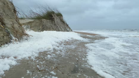 heavy winds blowing sea foam and sand dunes after hurricane force storm surge