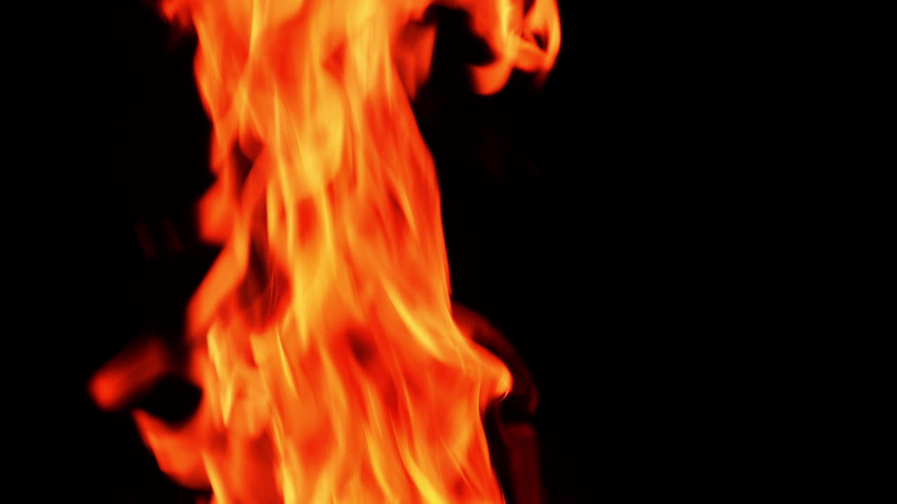 Hot orange flame burning. Close up. Beautiful fire tongues moving at the black backdrop.