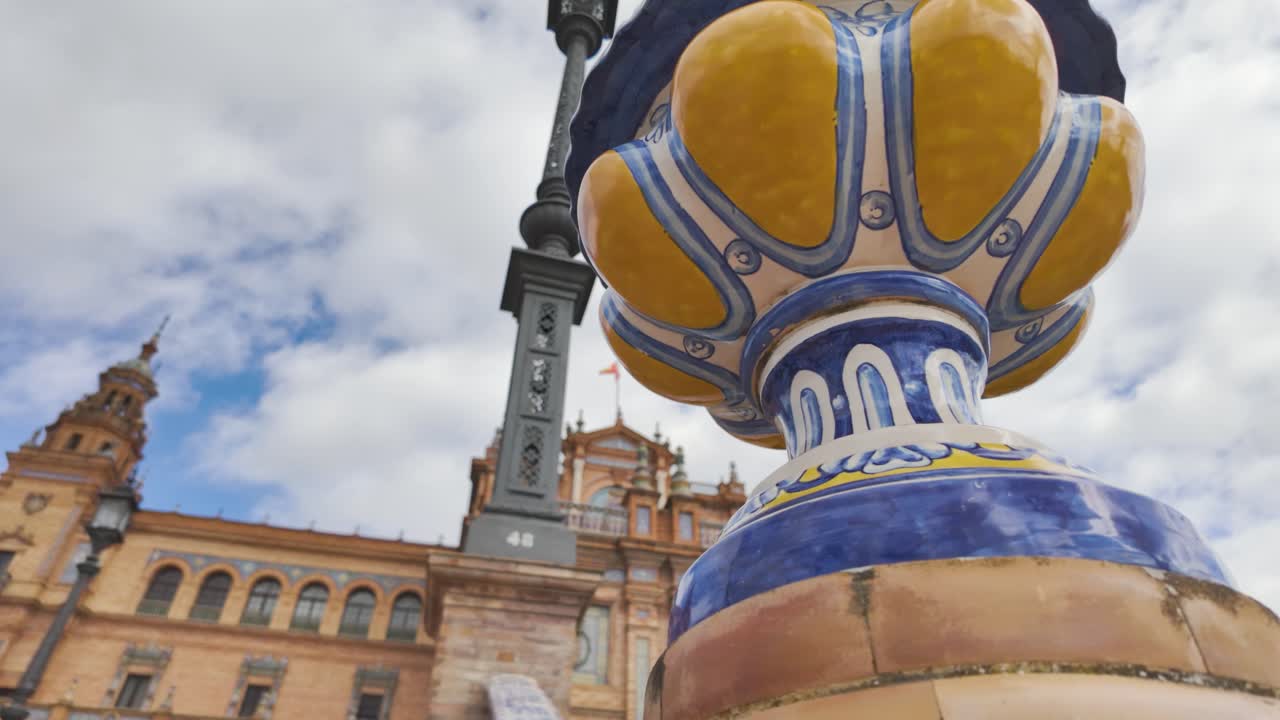 Traditional ceramic vase contrasting with the vibrant colors and intricate details of Plaza de Espana in Seville under a cloudy sky