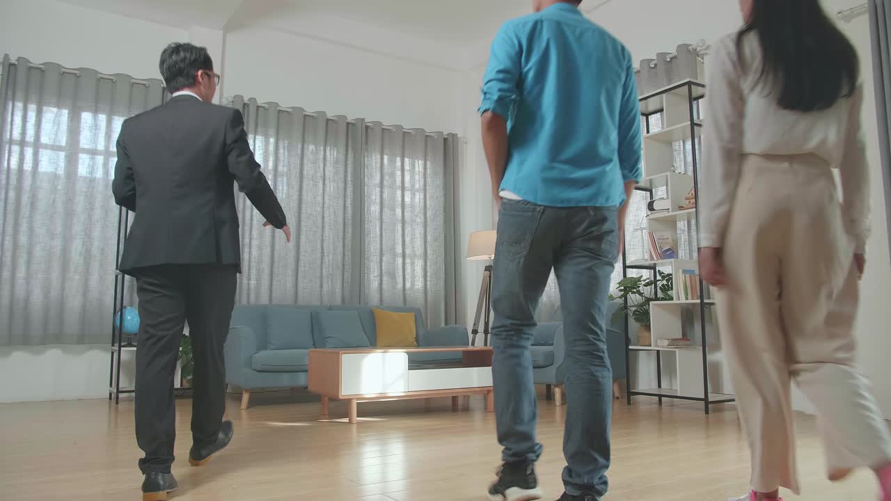 아시아 부동산 에이전트가 부부를 안내하여 집 안쪽을 판매합니다.