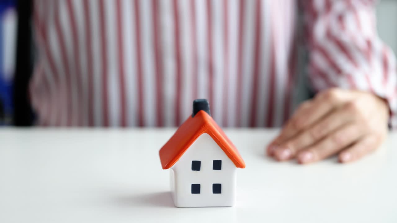 seguro de bienes raíces. agente de seguros con paraguas sobre la casa