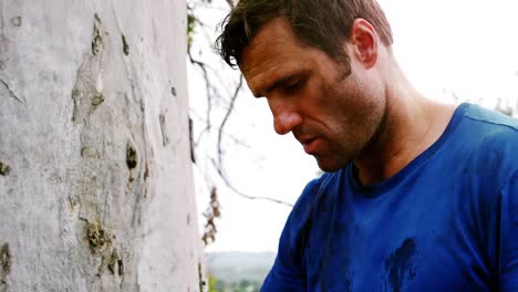 Tired-man-standing-against-a-tree-trunk