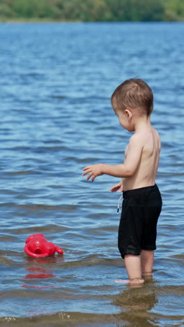 child playing on a river beach. summer water pond playground. vertical video