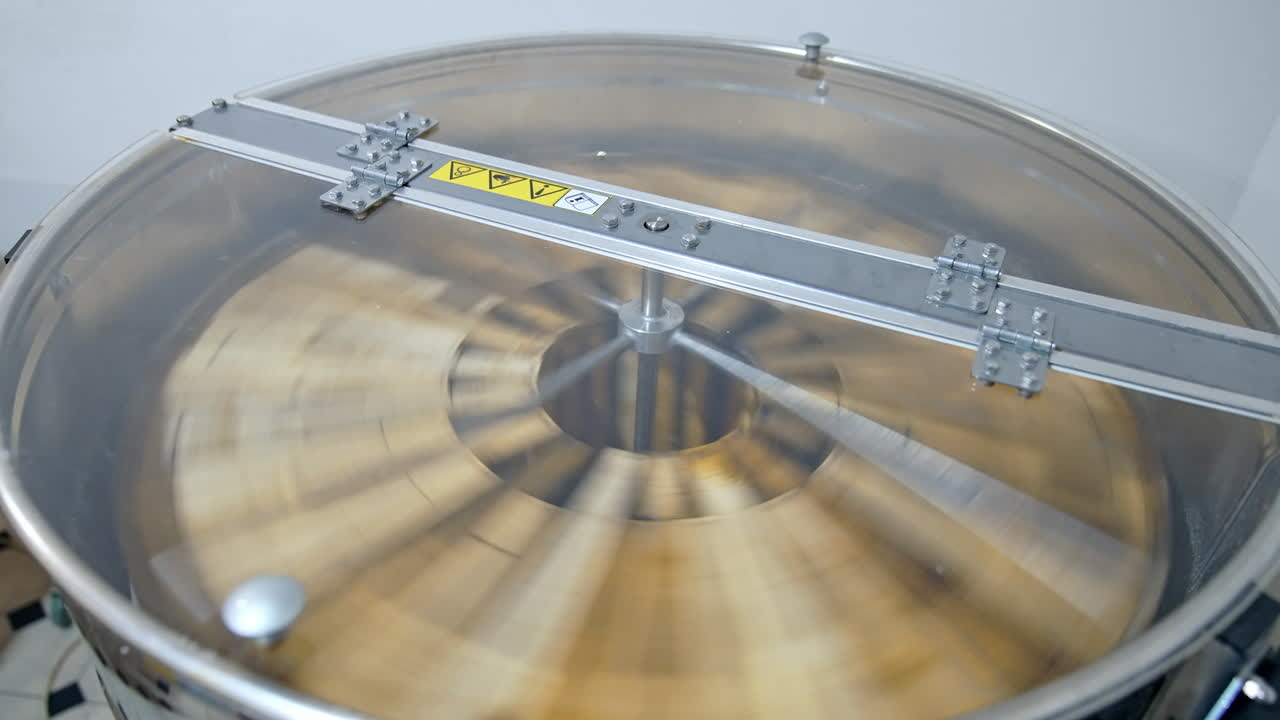 Beekeeping technology for making fresh honey from honeycomb. Honey extractor machine working. Centrifuge with frames spinning. Honey production.