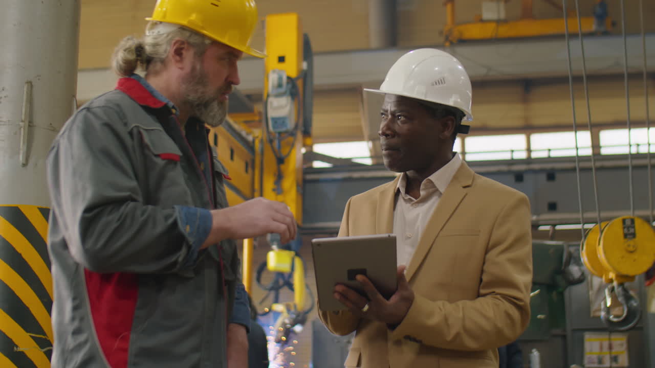 Ingenieros diversos usando una tablet y discutiendo el trabajo en una fábrica