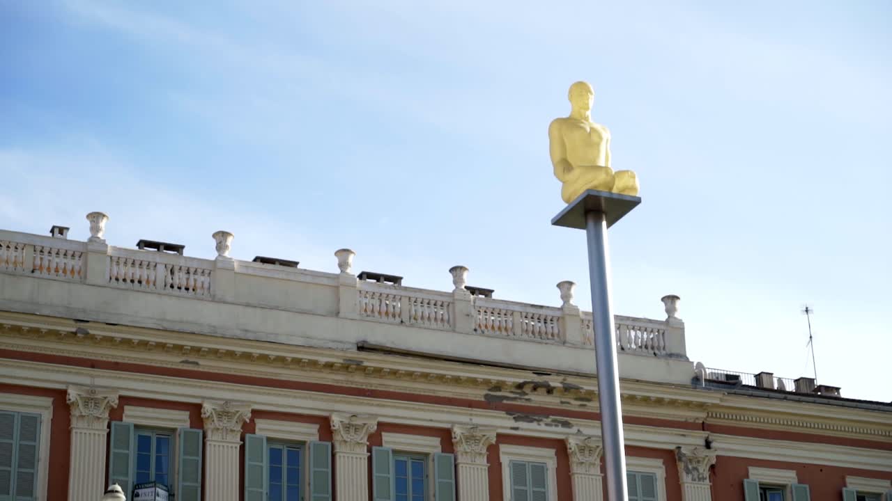 Gold Statue on a Pole in a City