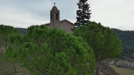 Rustic-cross-among-lush-green-trees-in-the-Old-Town-of-Oristas,-Barcelona,-Spain