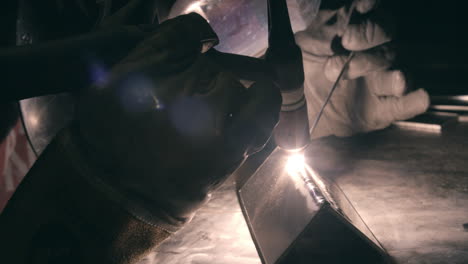 close up of welder wearing protective gloves working in factory