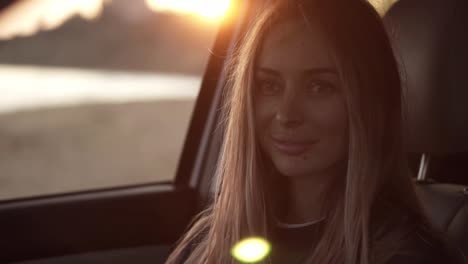 hermosa mujer mirando a la cámara desde el coche y luego salir del asiento del coche a la orilla del mar