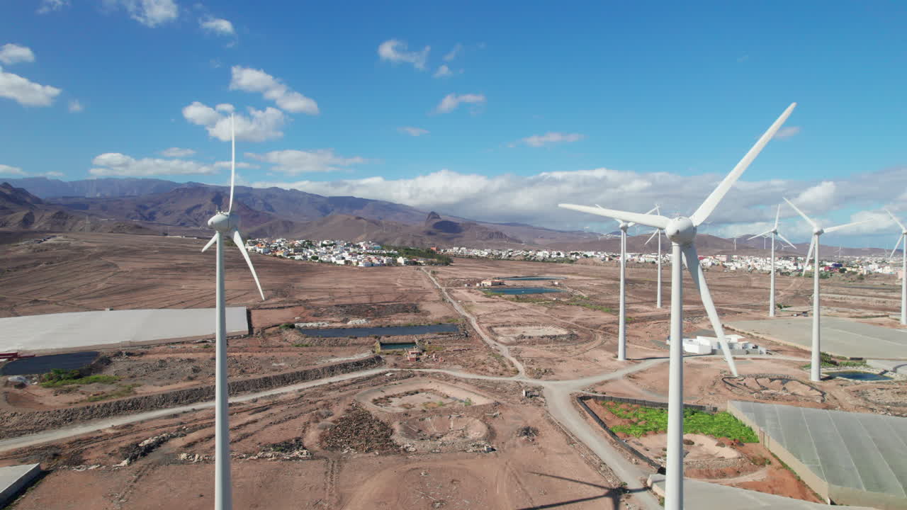vista aérea que pasa sobre un campo de turbinas eólicas en un paisaje desértico en la isla de gran canaria en un día soleado